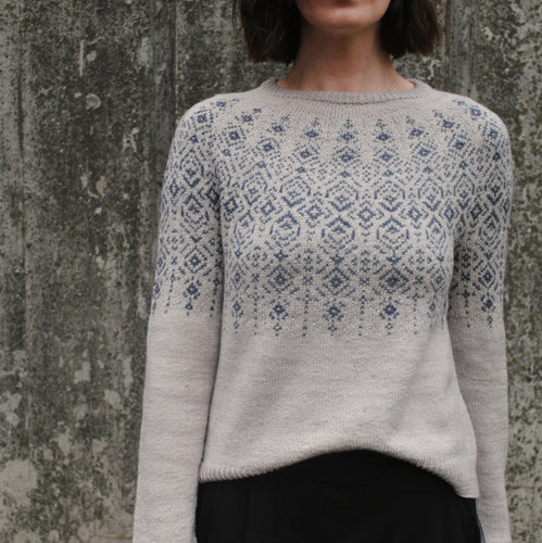 A person wearing a beige and blue geometric patterned sweater.